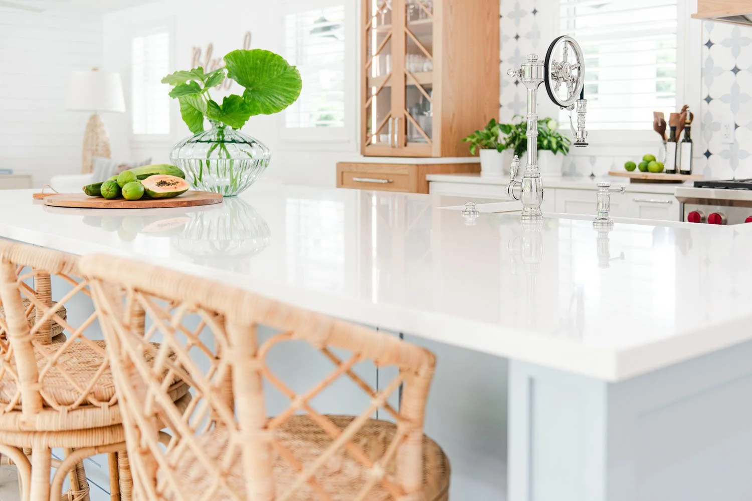 White quartz island countertop with rattan stools and monstera leaves