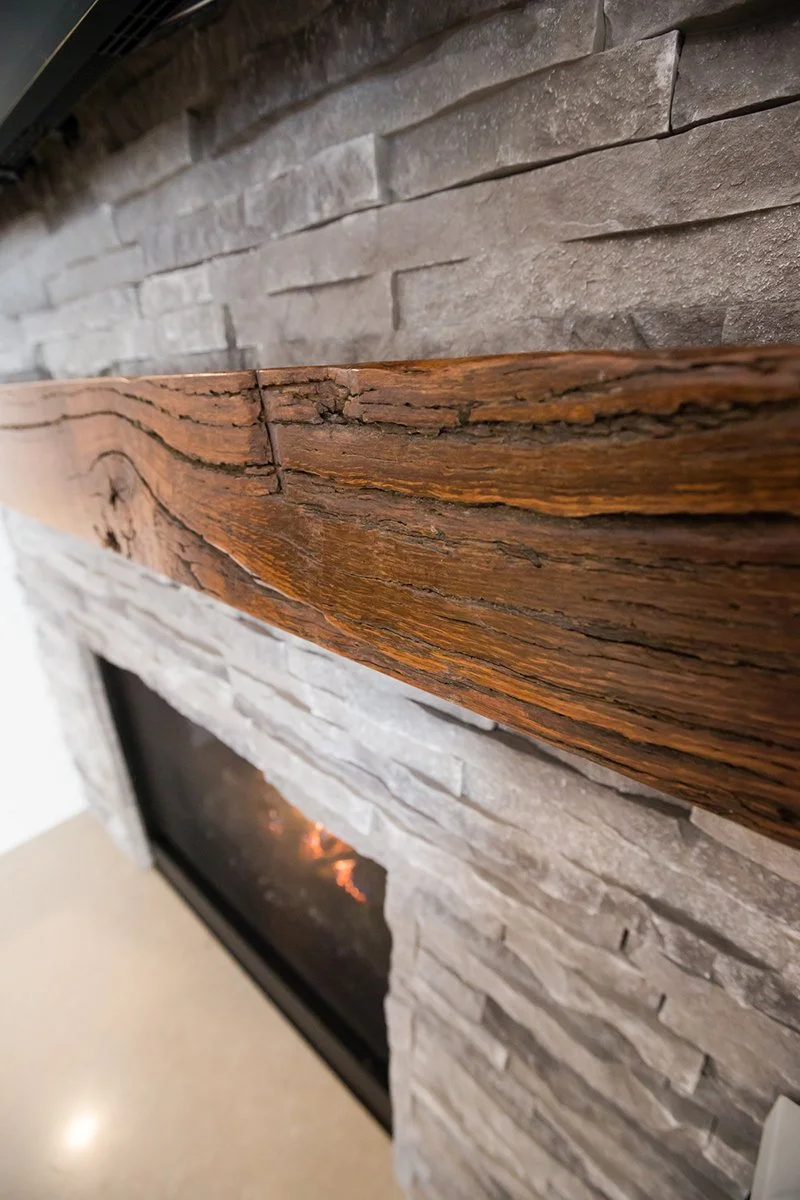 Close-up of reclaimed wood mantel on a stacked stone fireplace