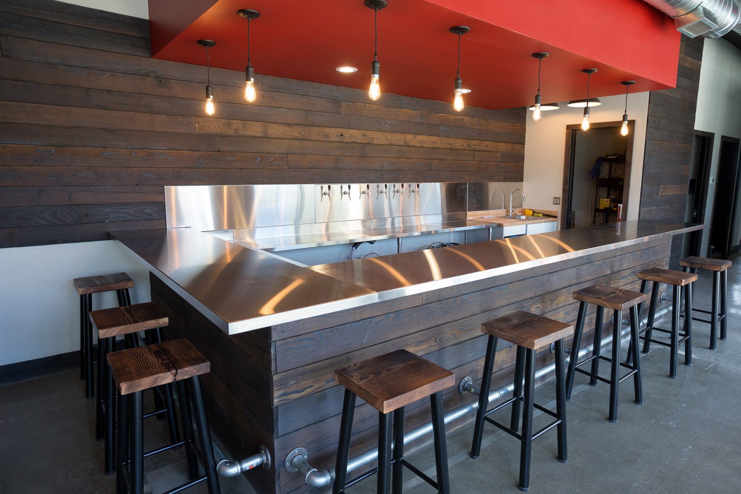 Taproom bar with stainless counter and wood stools