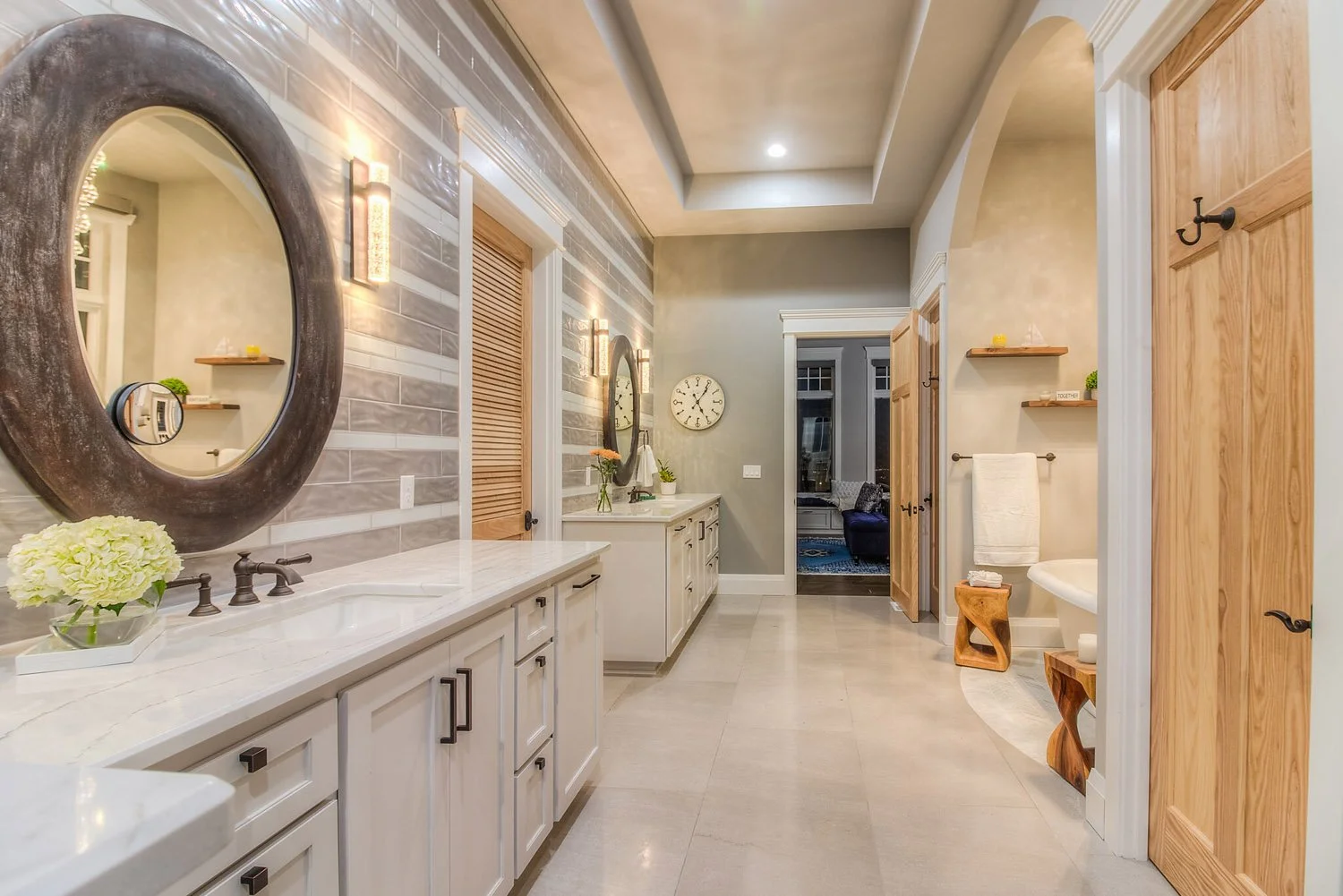 Primary bathroom with round mirror and freestanding tub beyond