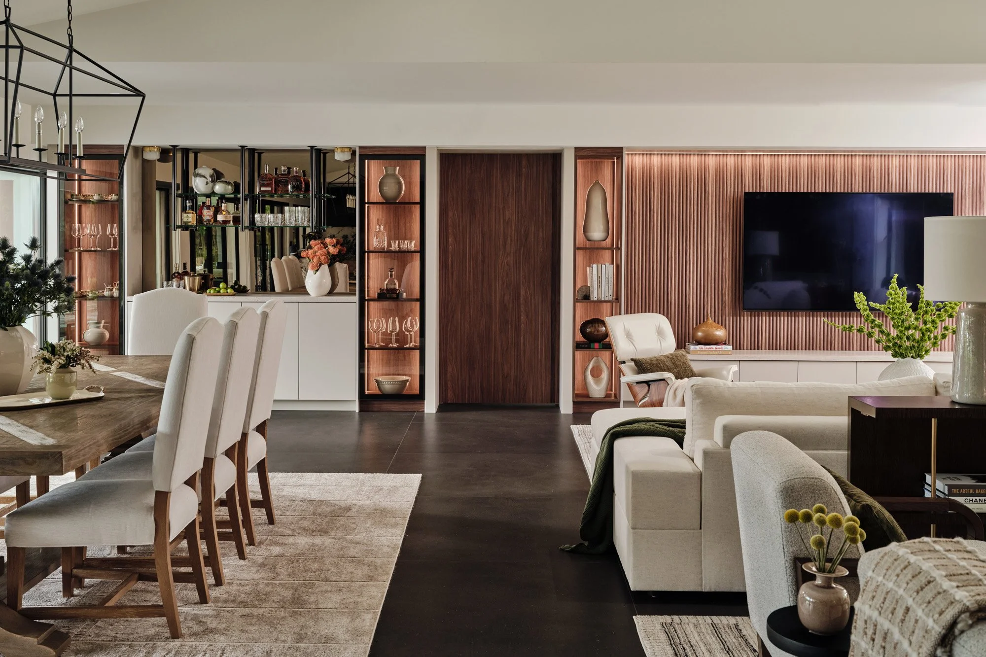 Long view of great room with dining table and walnut media wall
