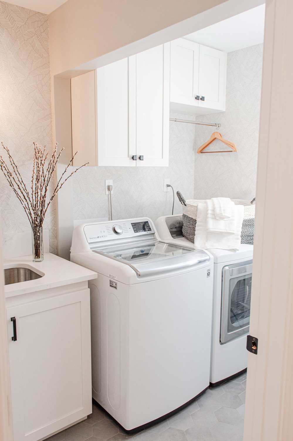Laundry room with white washer and dryer and utility sink