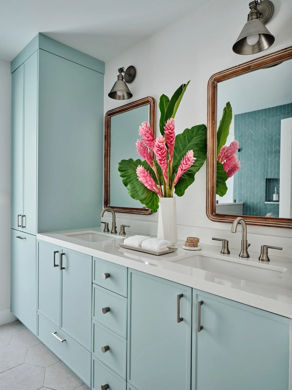 Light blue double vanity with wood mirrors and pink ginger flowers