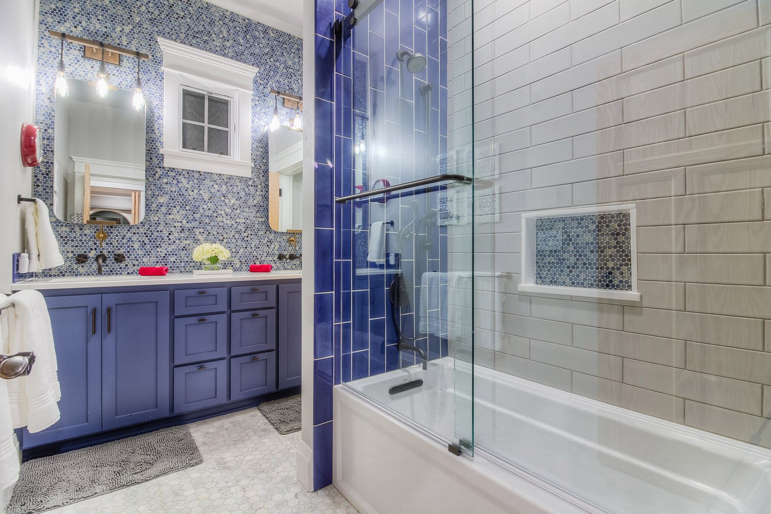 Bathroom with navy vanity, blue tile shower and glass door