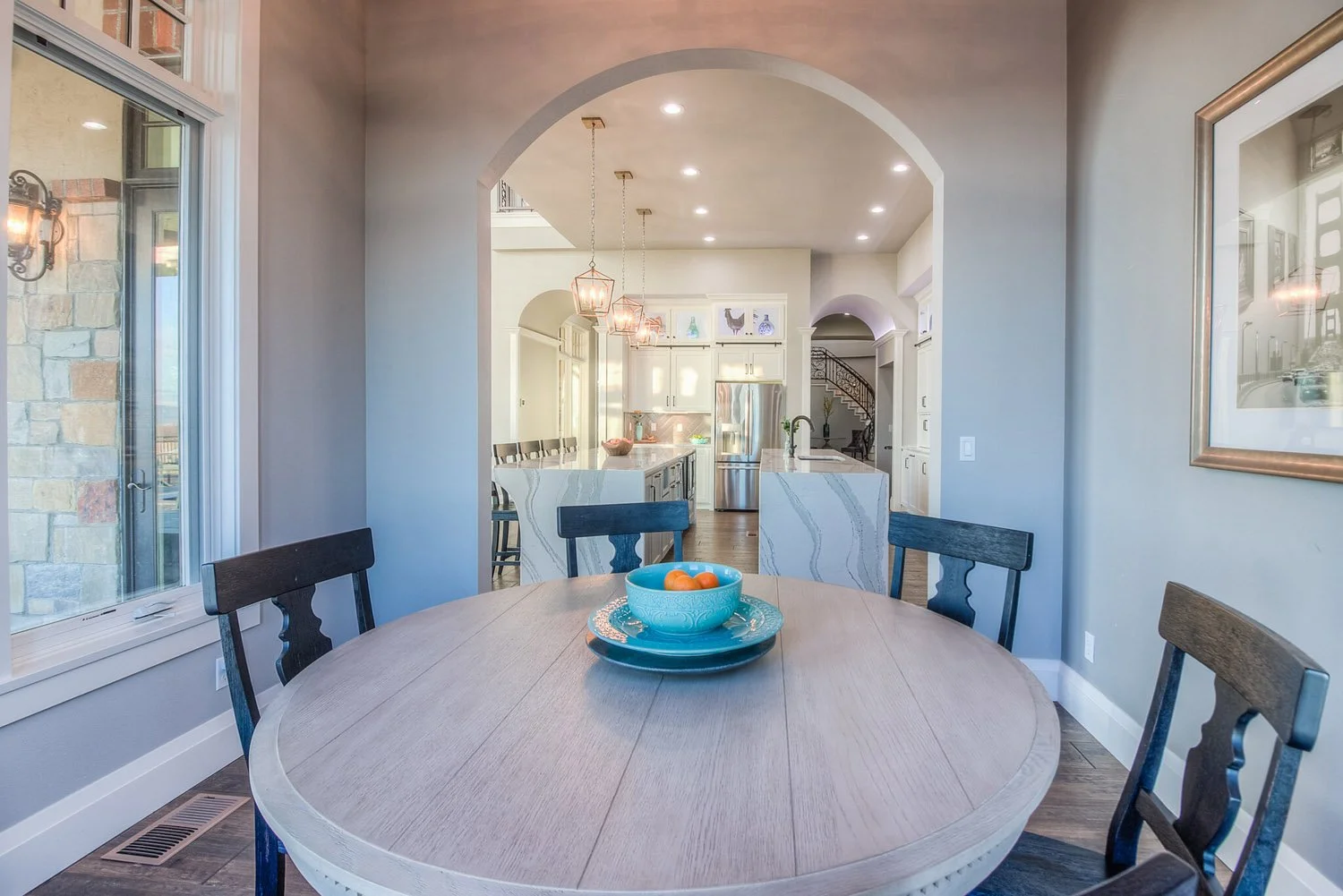 Round dining table with black chairs under an arched opening