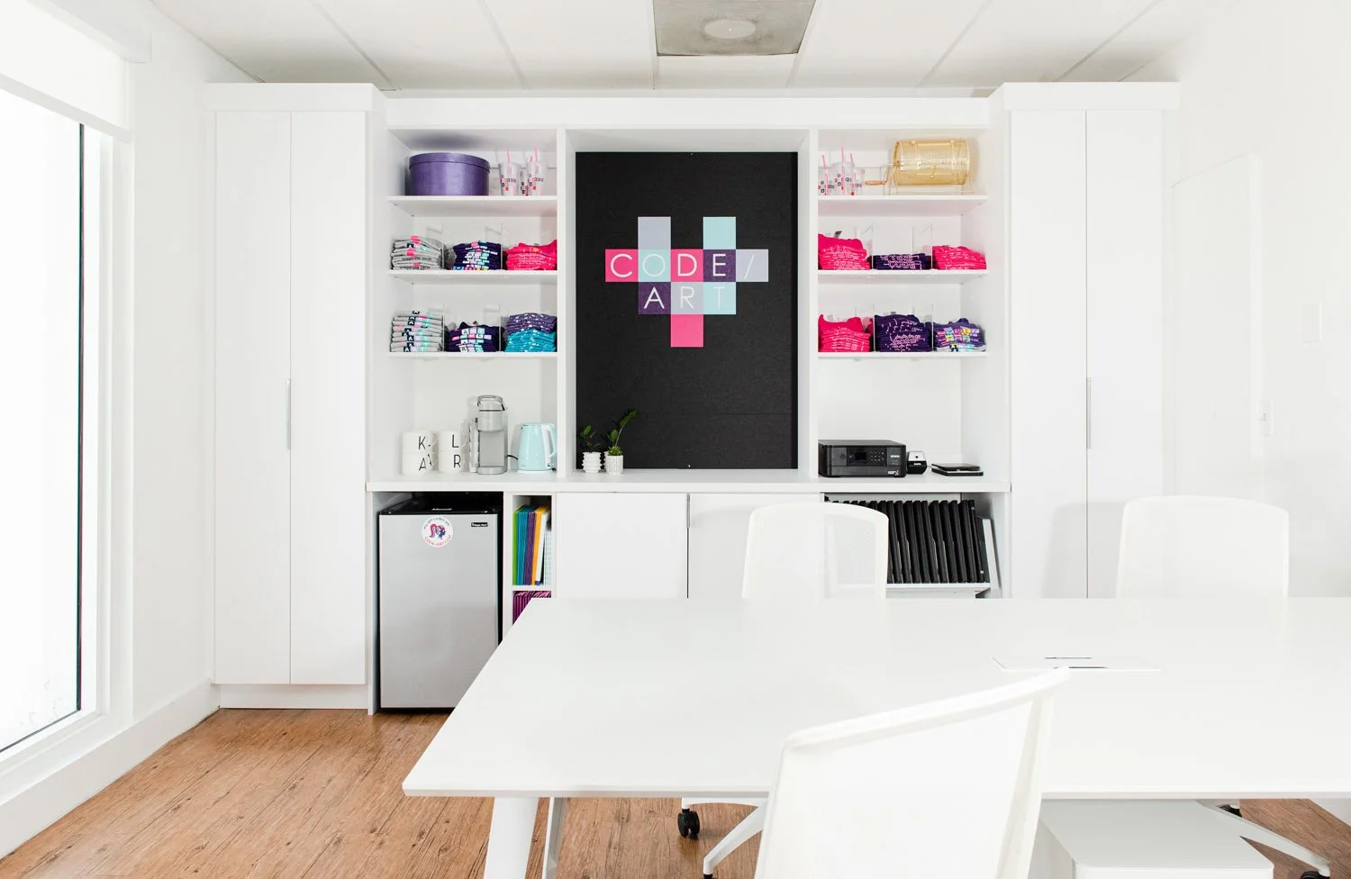 White conference table in front of built-in shelves and black accent panel