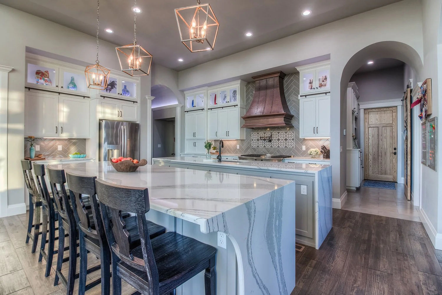 Kitchen island with black counter stools and pendant lights