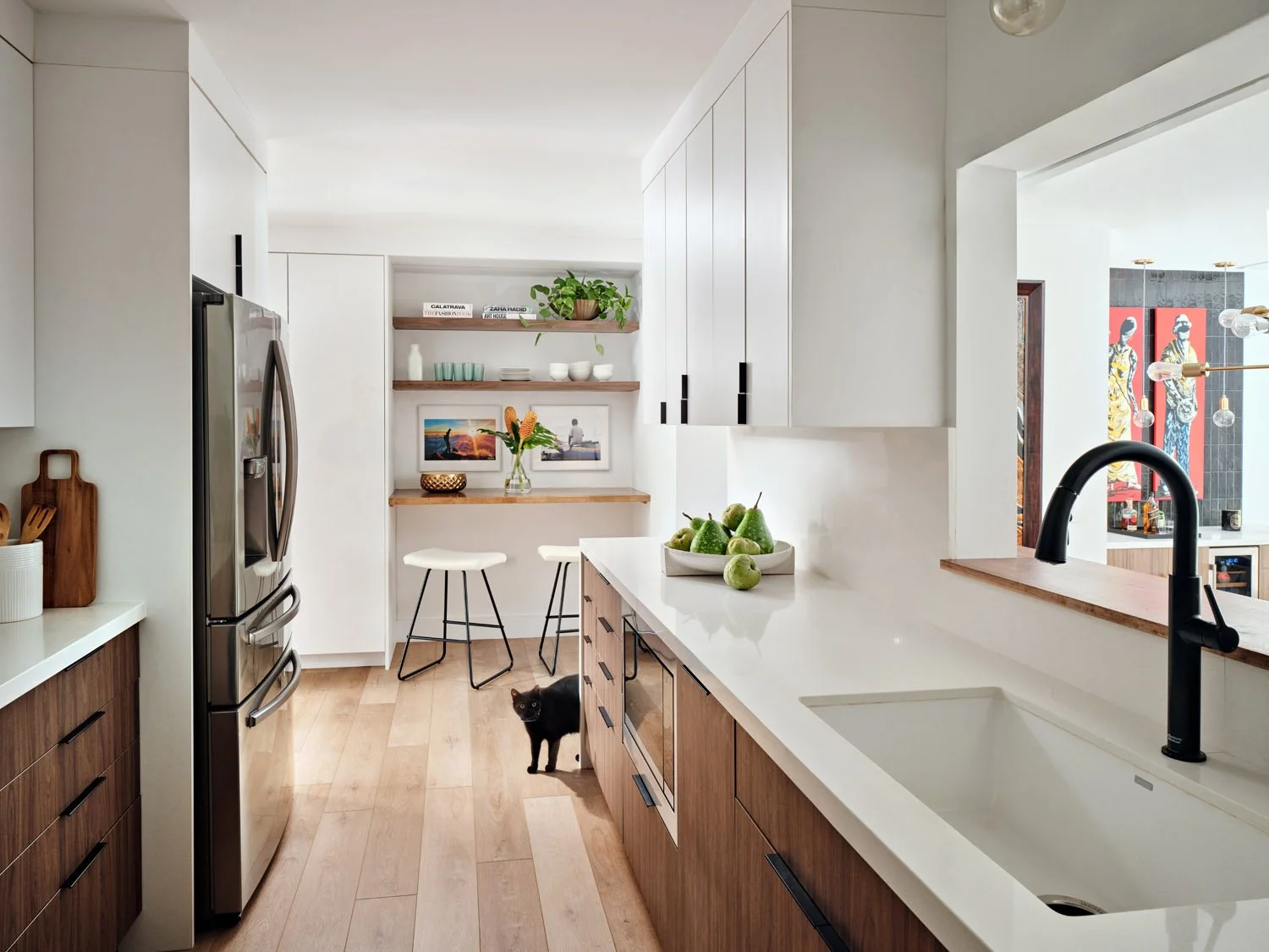 Galley kitchen with white quartz counters and black faucet looking toward breakfast nook