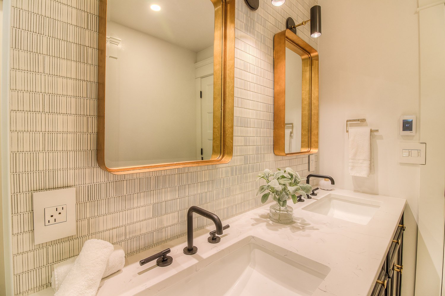 Subway tile wall with brass mirrors over a white counter