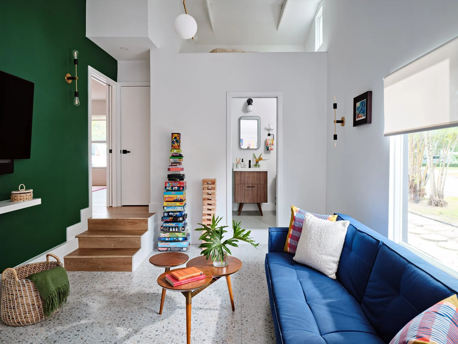 Family room with navy sofa, wood coffee table and green accent wall