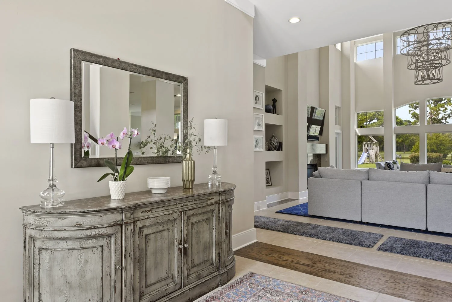 Console with mirror and lamps beside a view into the great room
