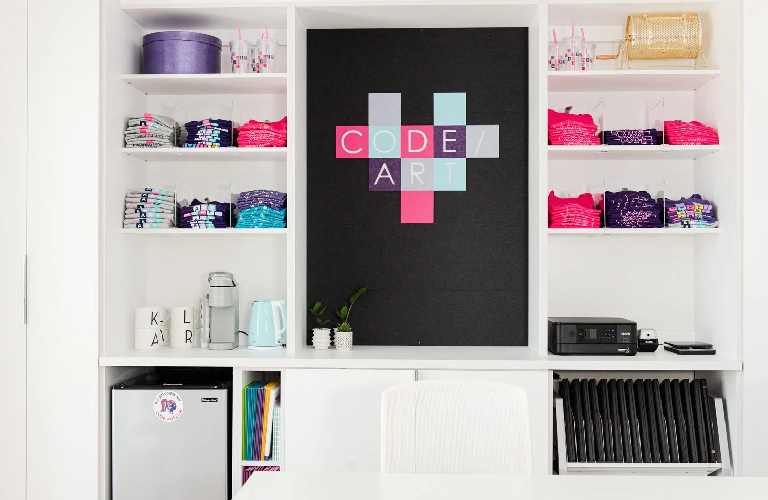 Built-in white shelving with colorful storage bins and black accent panel