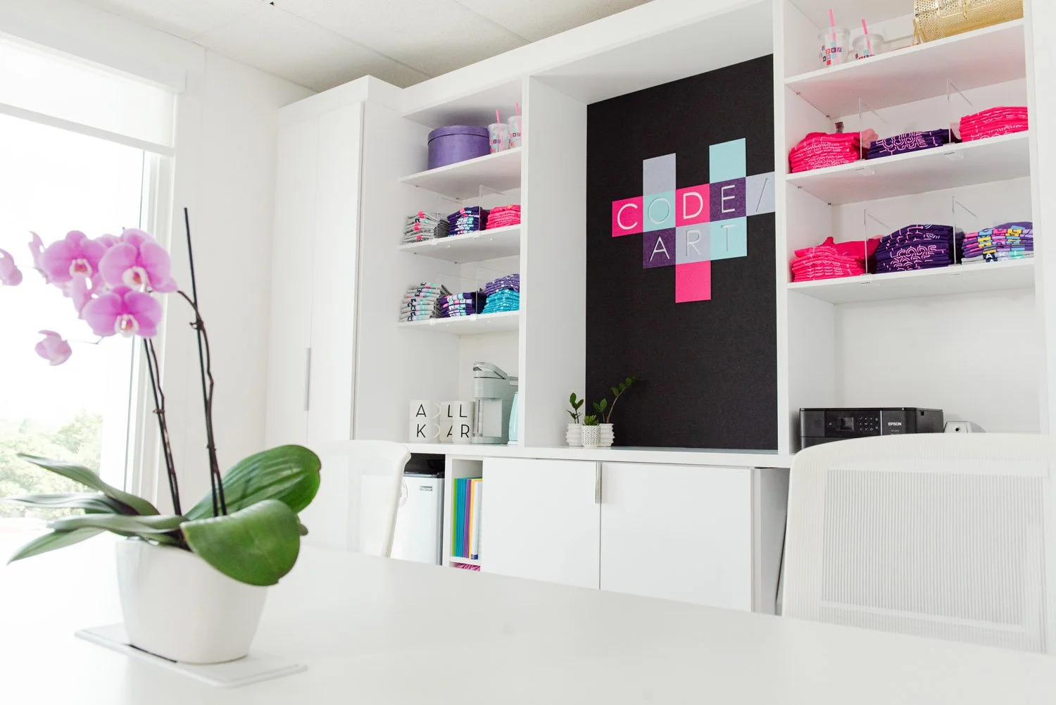 Pink orchid on a white table in front of built-in shelving