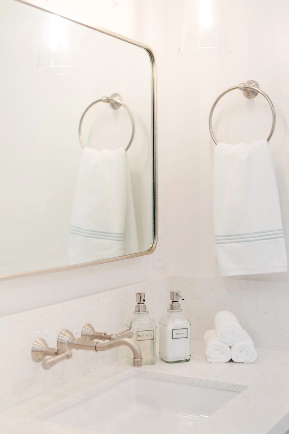 Rounded mirror and towel ring above a wall-mounted faucet