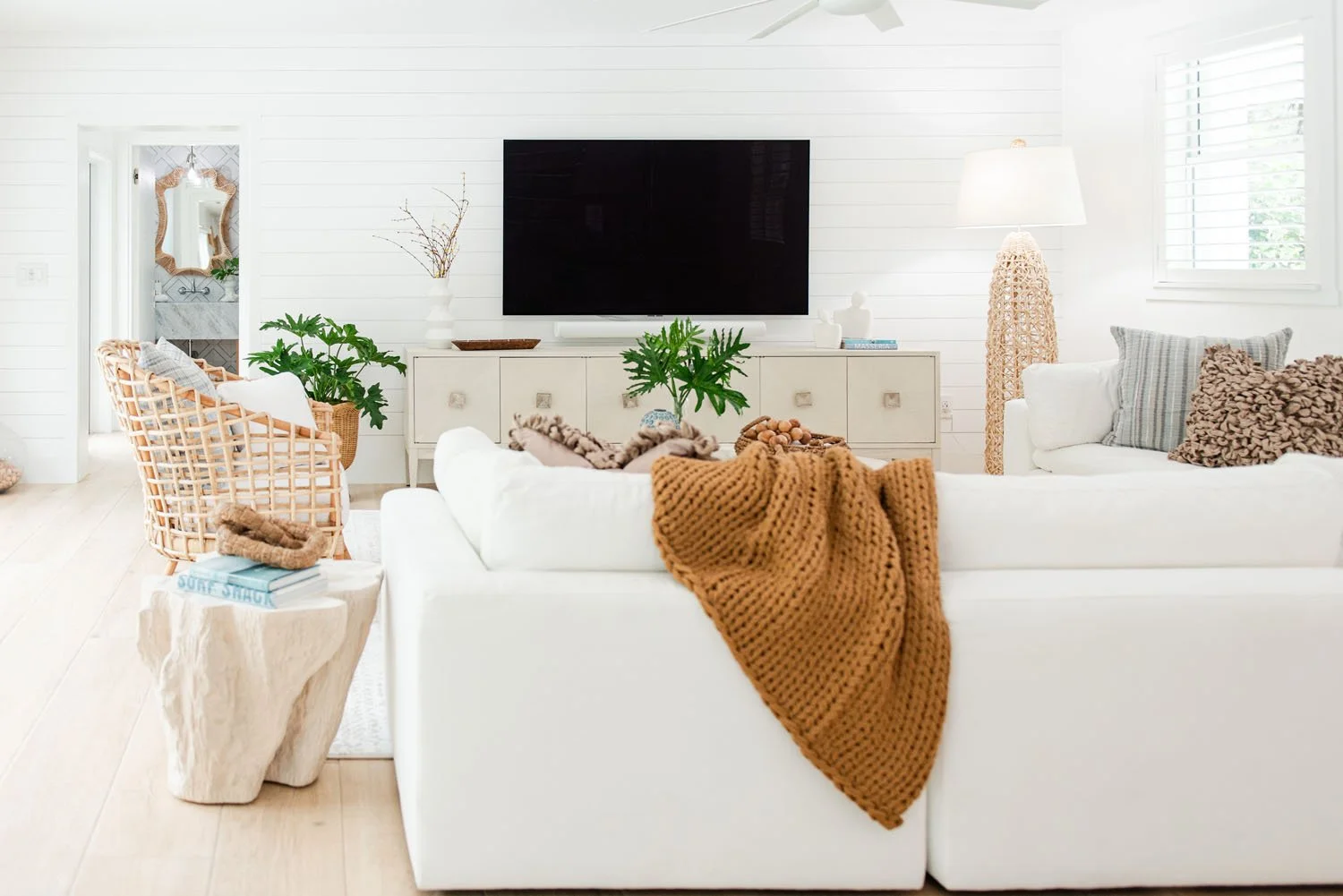 Living room with white sectional, wall-mounted TV and white media console