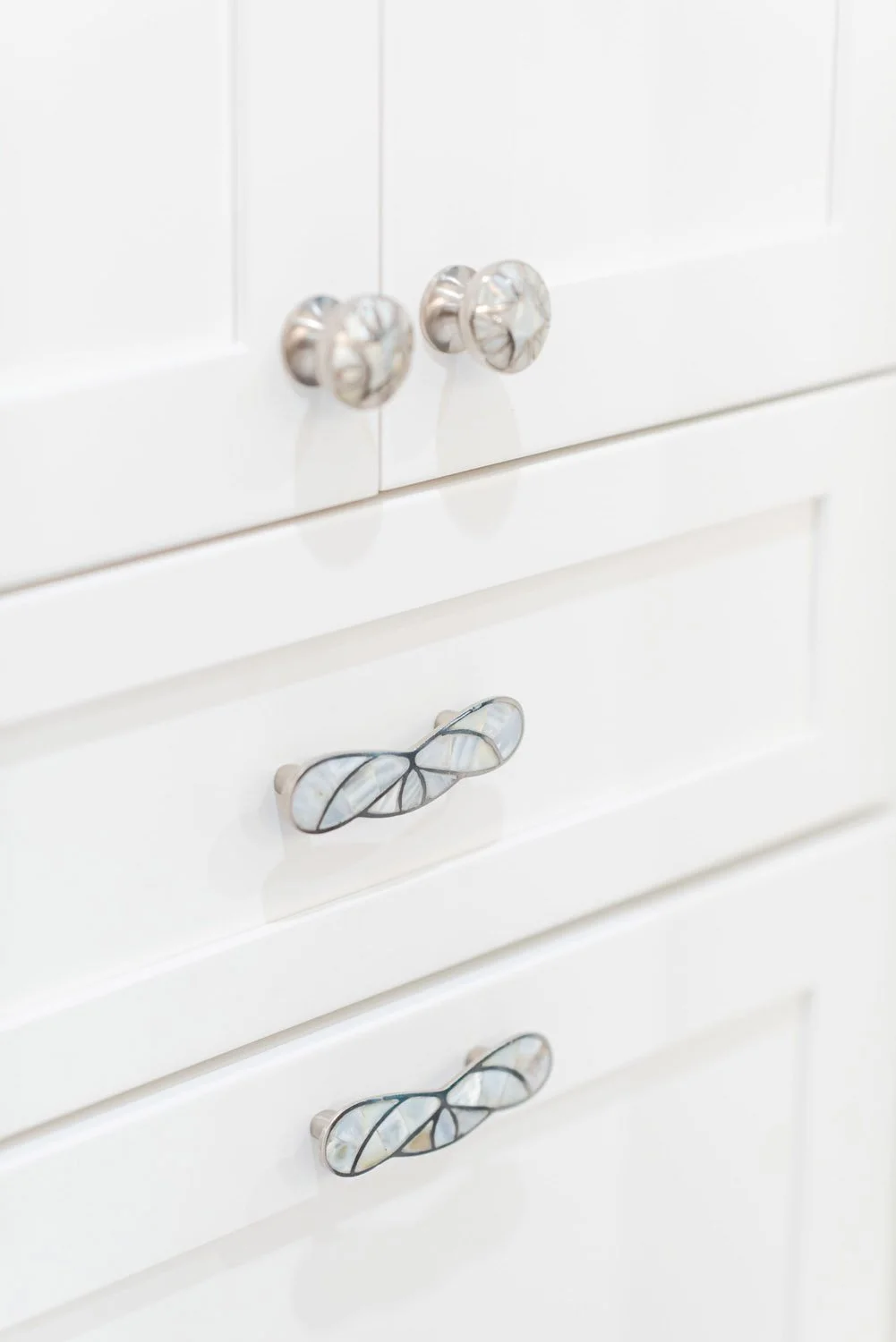 White cabinet drawers with crystal and leaf-shaped hardware
