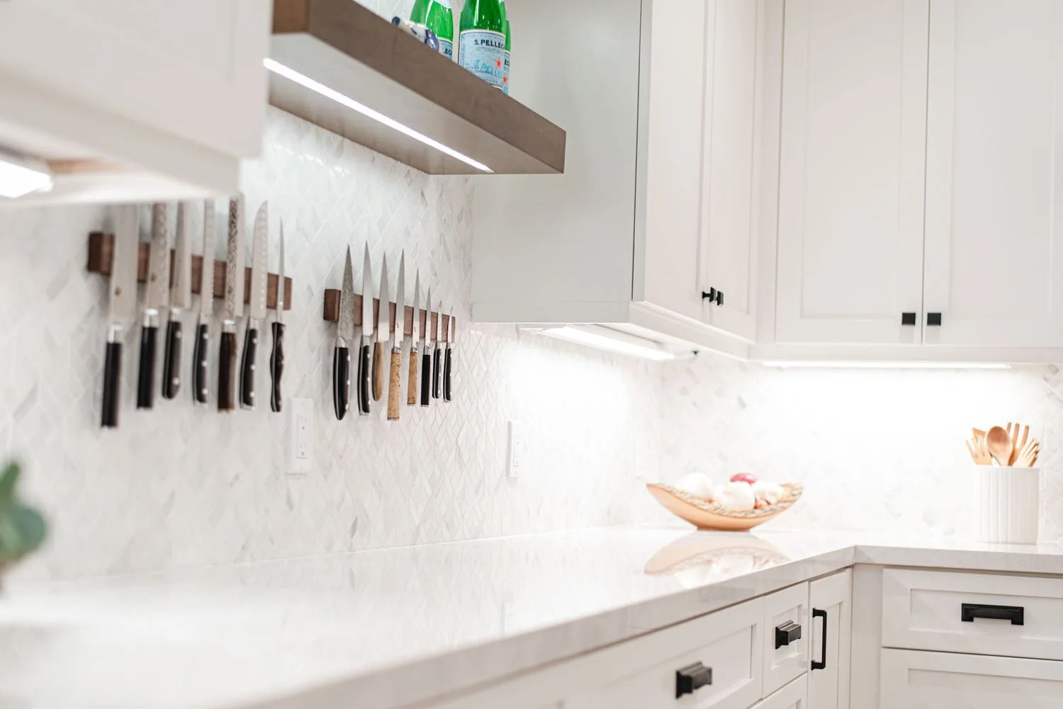 White kitchen with floating walnut shelves and knife display