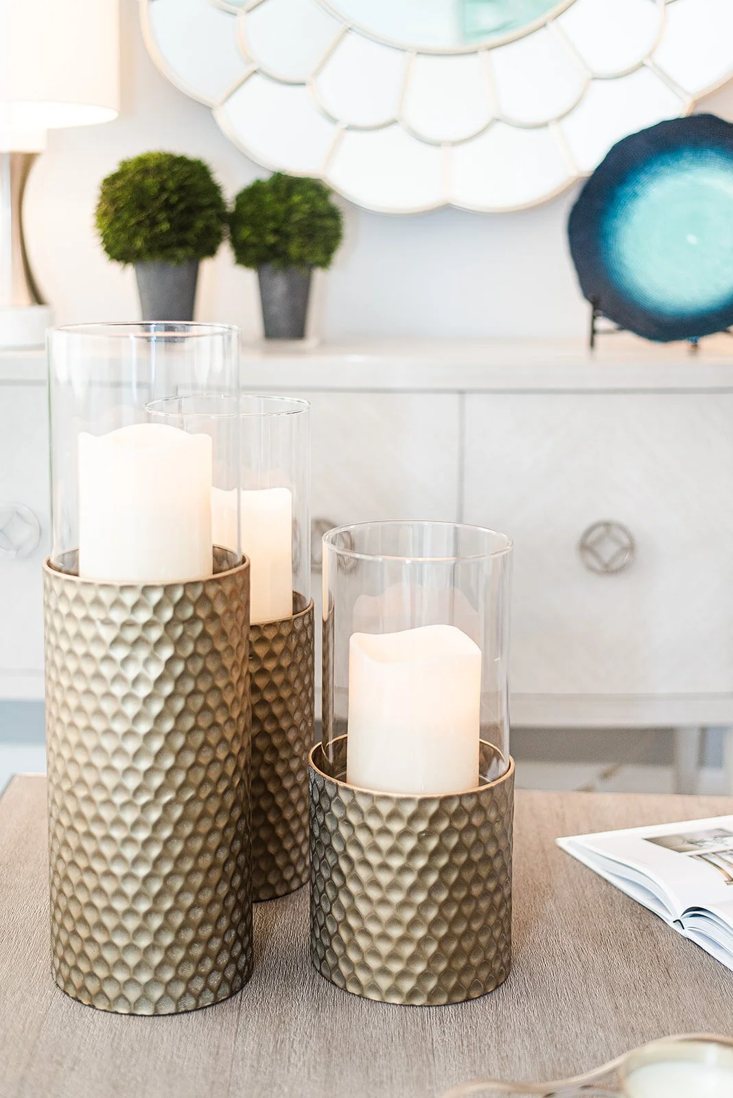 Gold mercury glass candle holders on a white sideboard