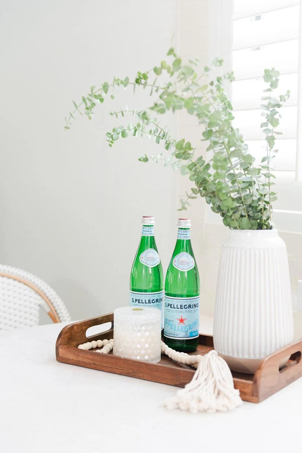 Sparkling water bottles and greenery on a wood tray