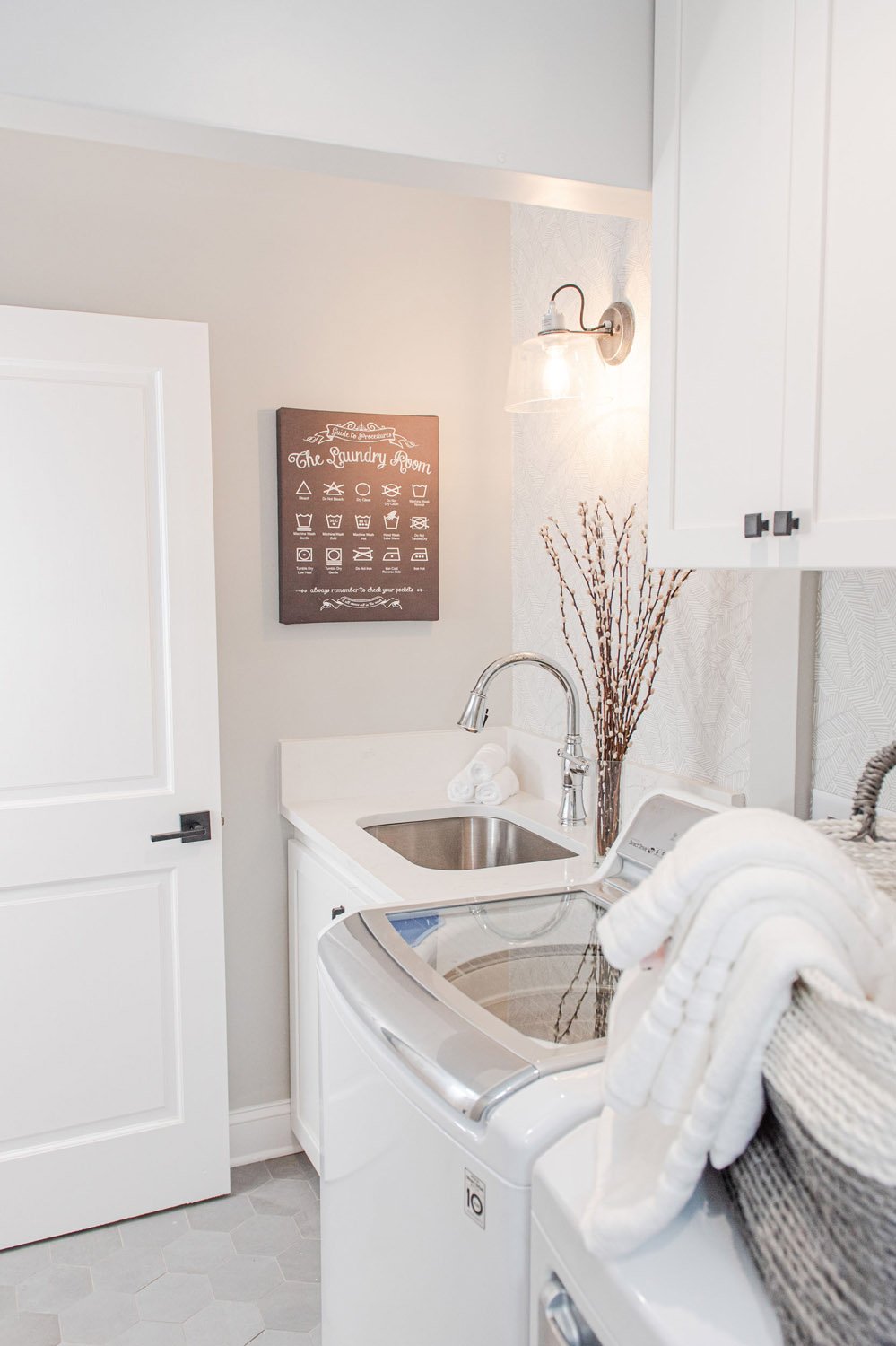 Laundry room with white door, utility sink and folded towels