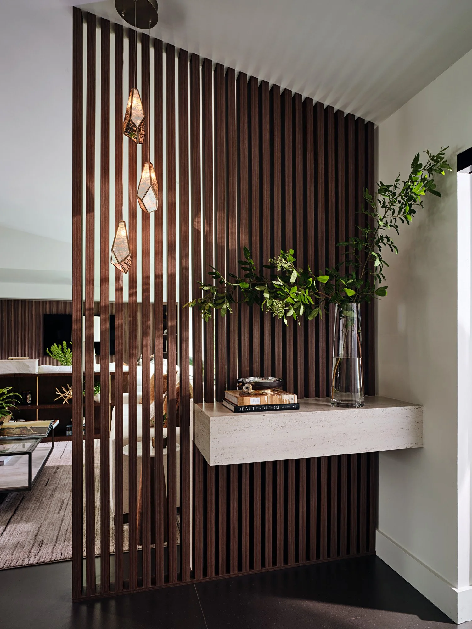 Foyer with walnut slat divider and floating ledge with greenery