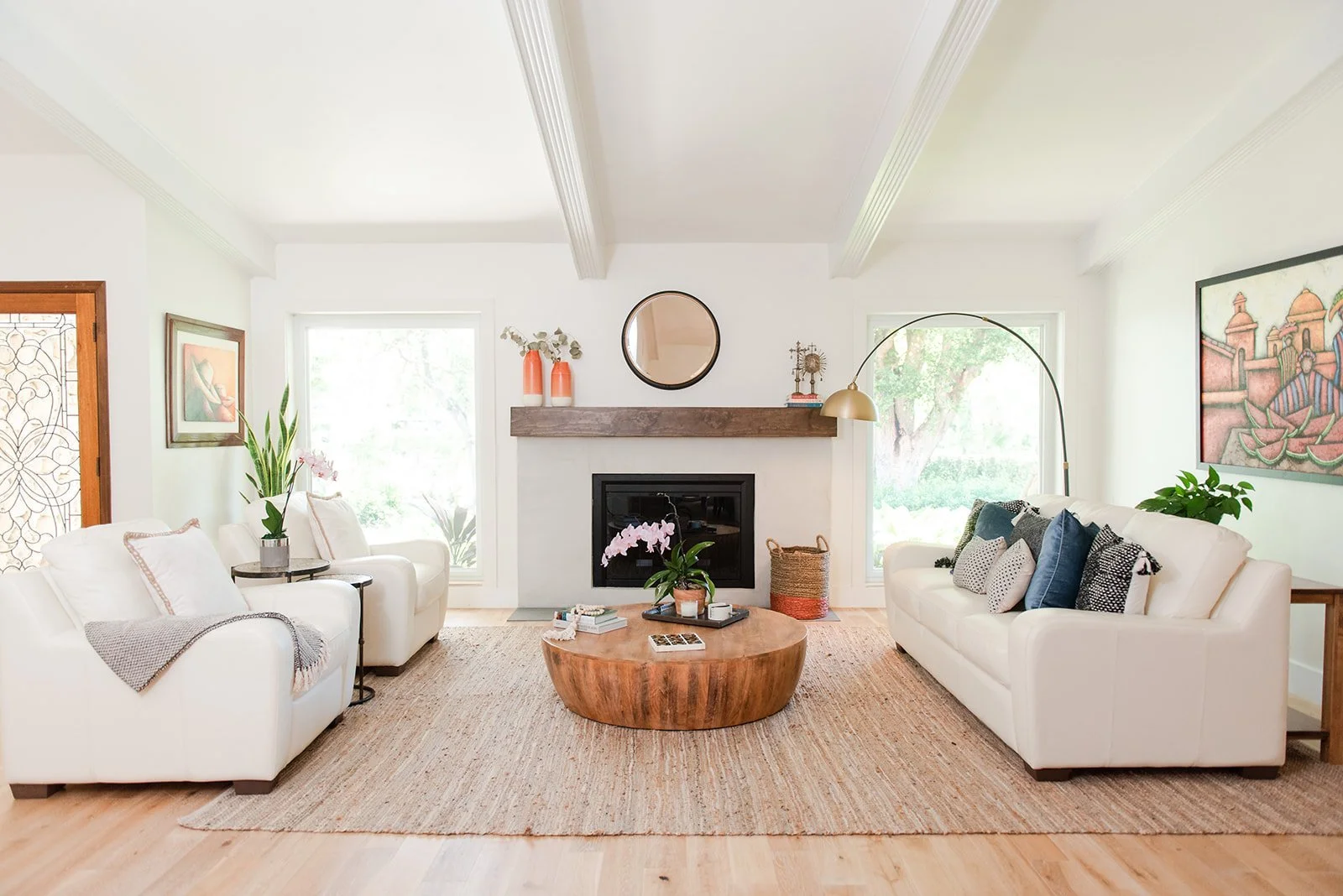 Living room with white sofas, round wood coffee table and fireplace