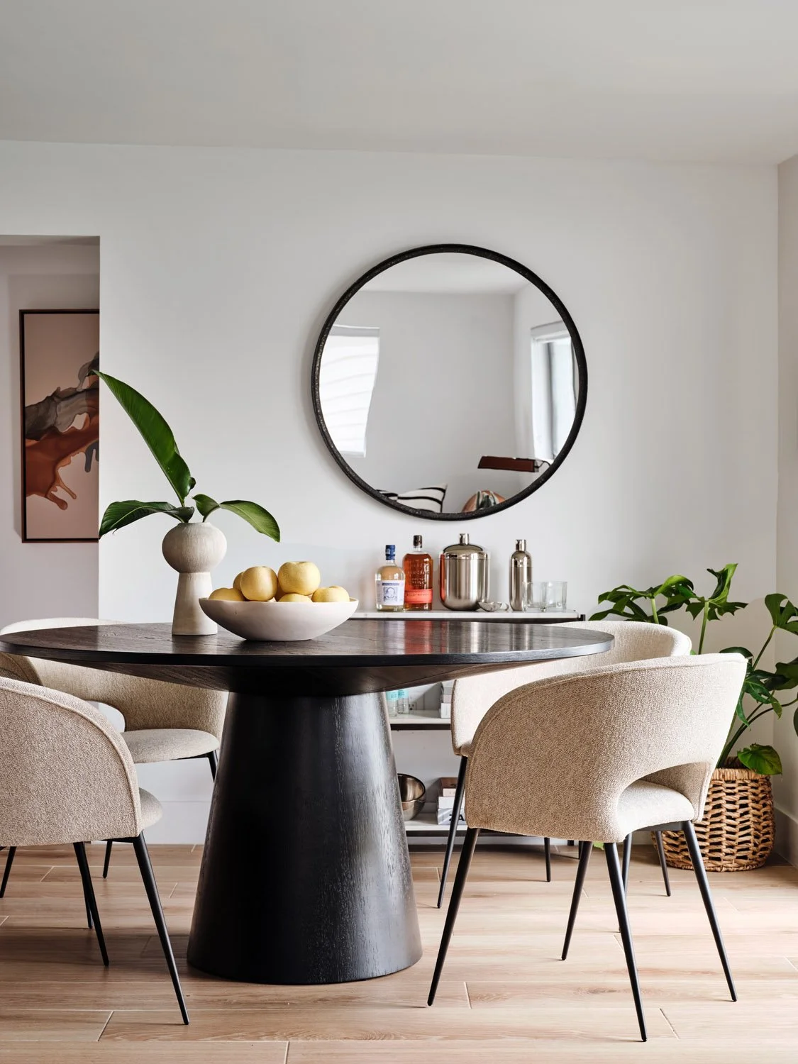 Dining nook with round black pedestal table and boucle chairs