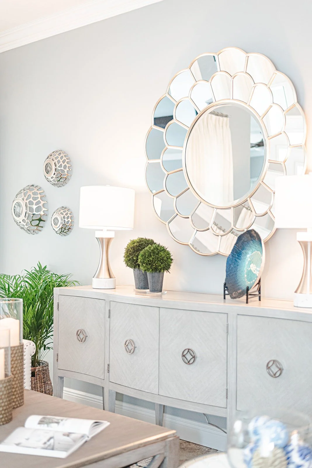White sideboard under a round scalloped mirror