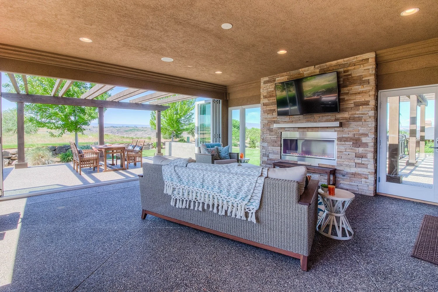 Covered sunroom with sofa facing a stone fireplace wall