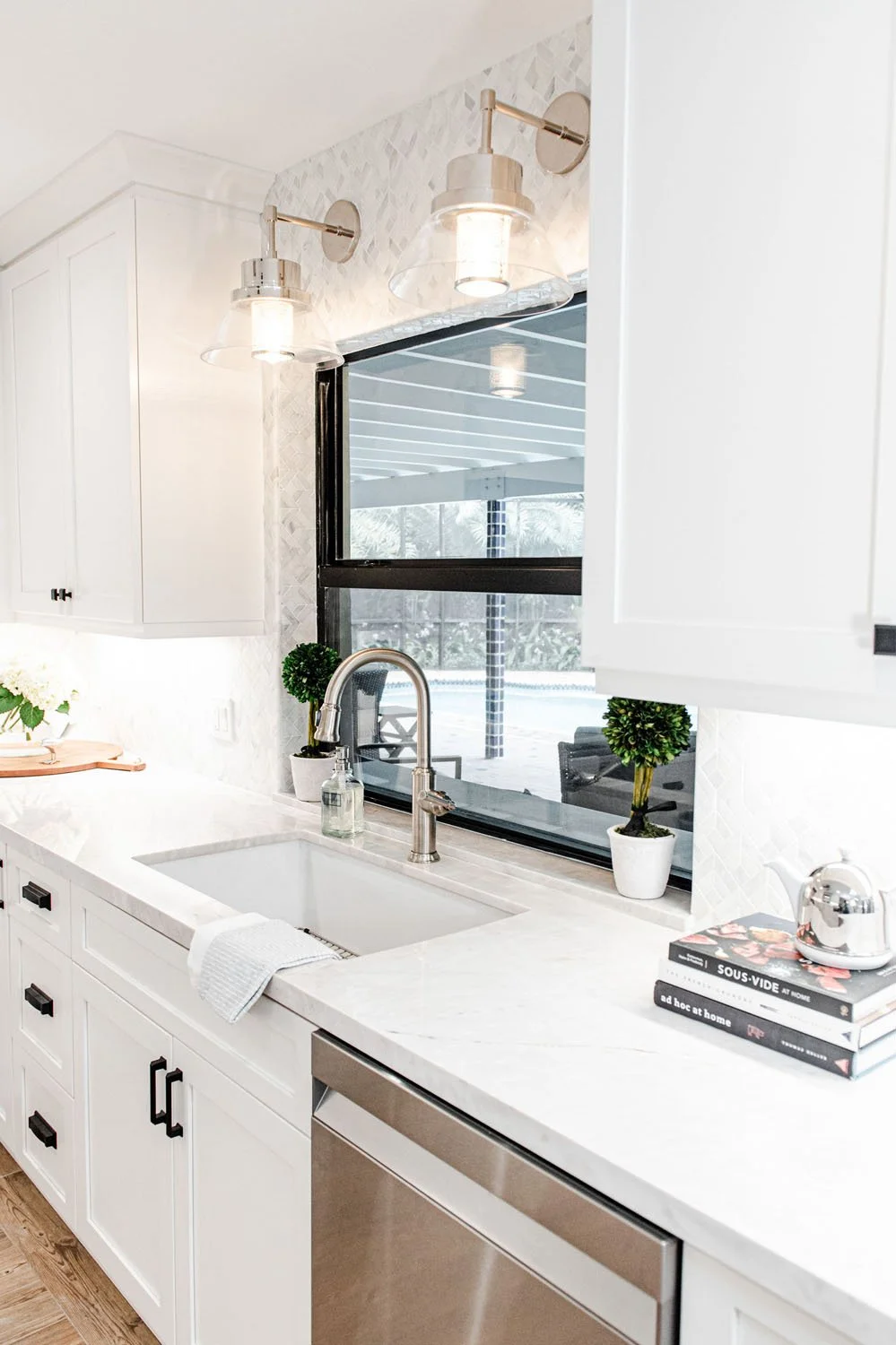 Kitchen sink with brass wall sconces and black window