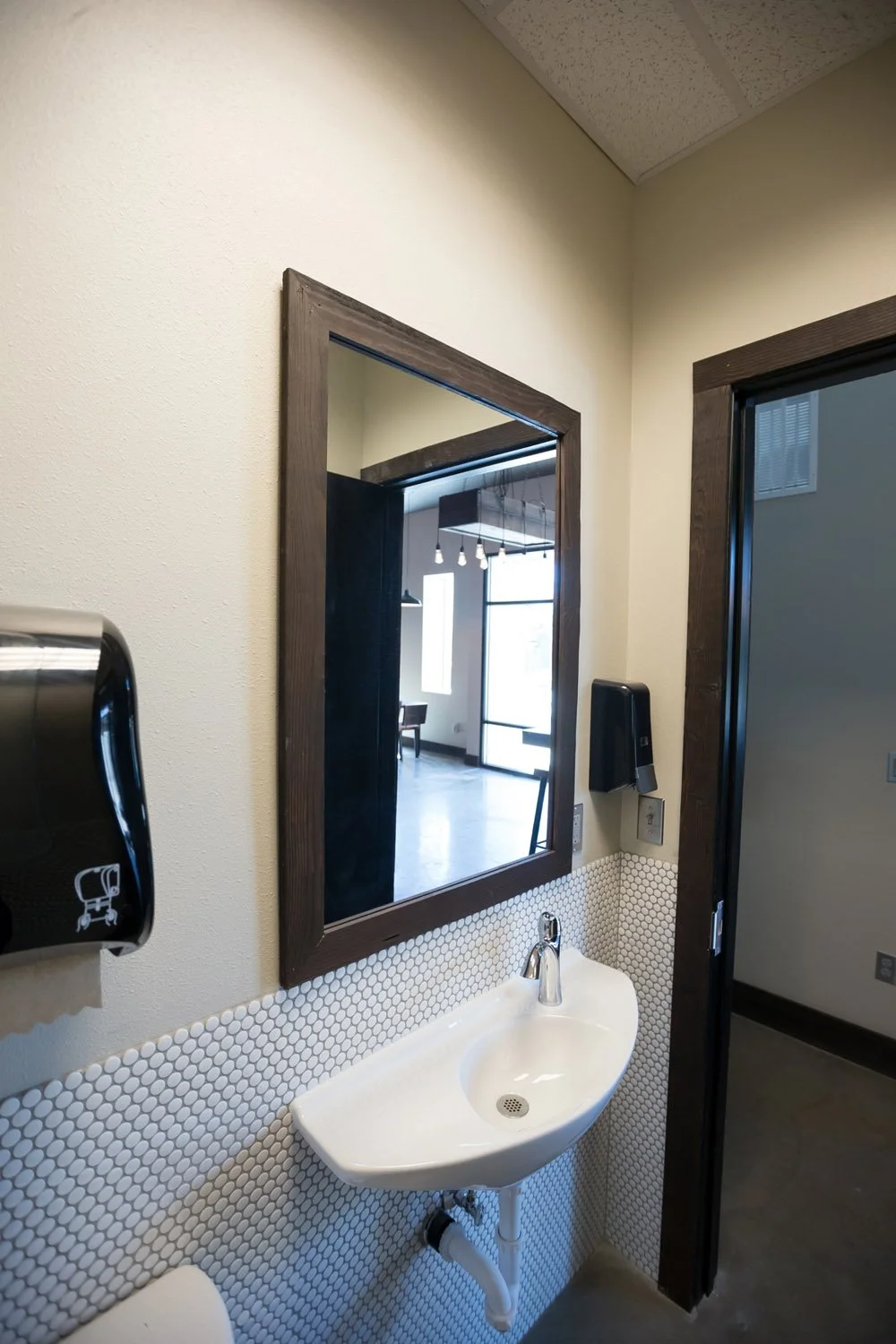 Restroom with wall-mounted sink and dark framed mirror