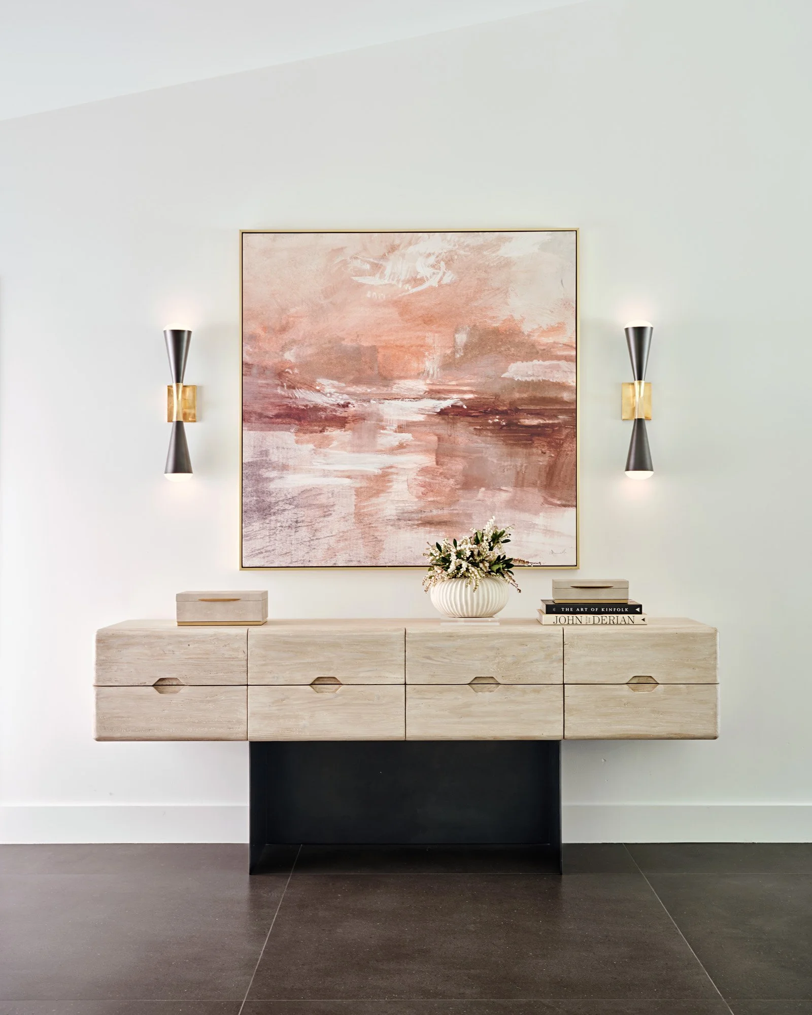 Floating cream console with wall sconces and blush abstract painting