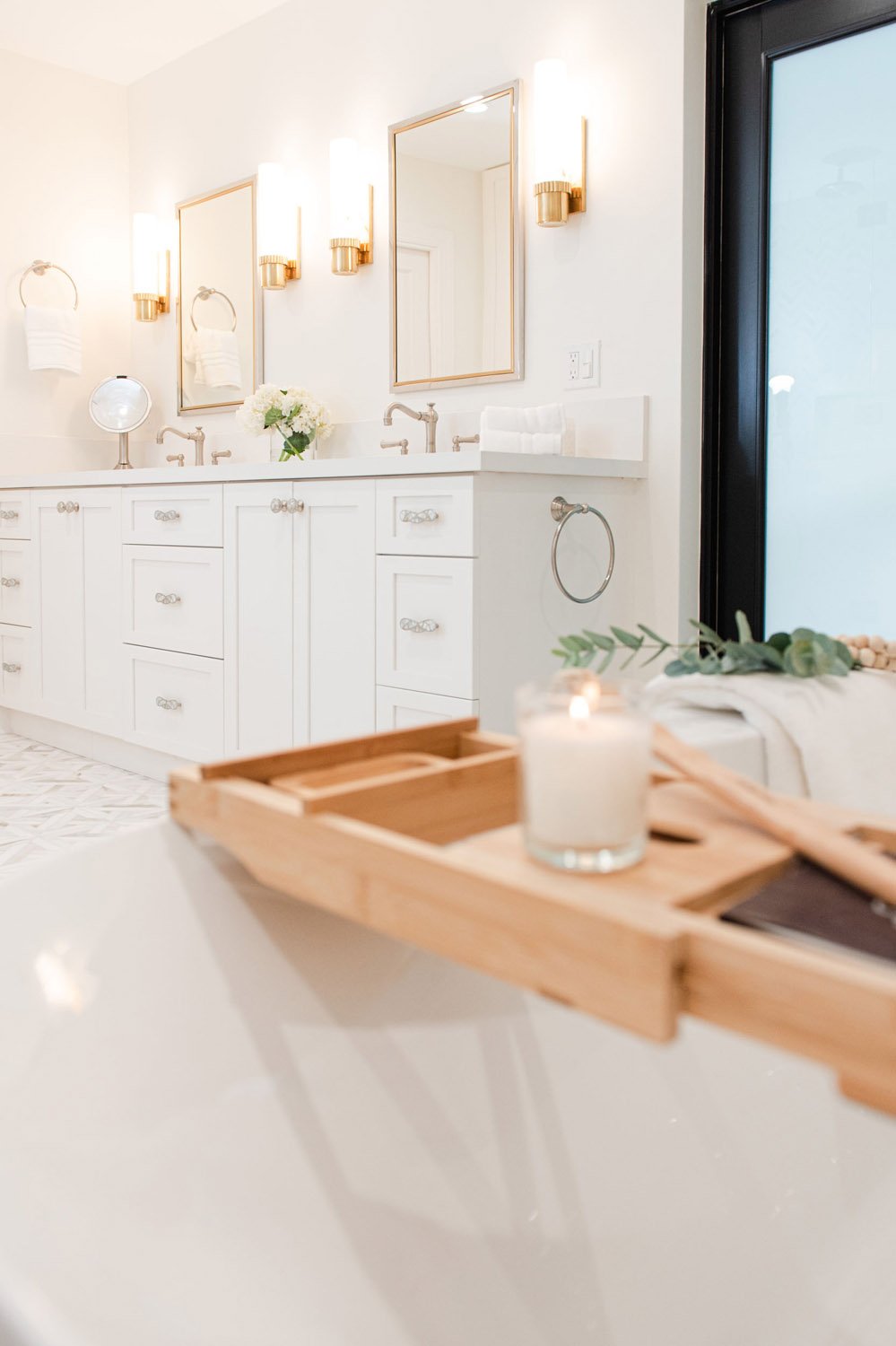 Double vanity with brass sconces and wood bath tray