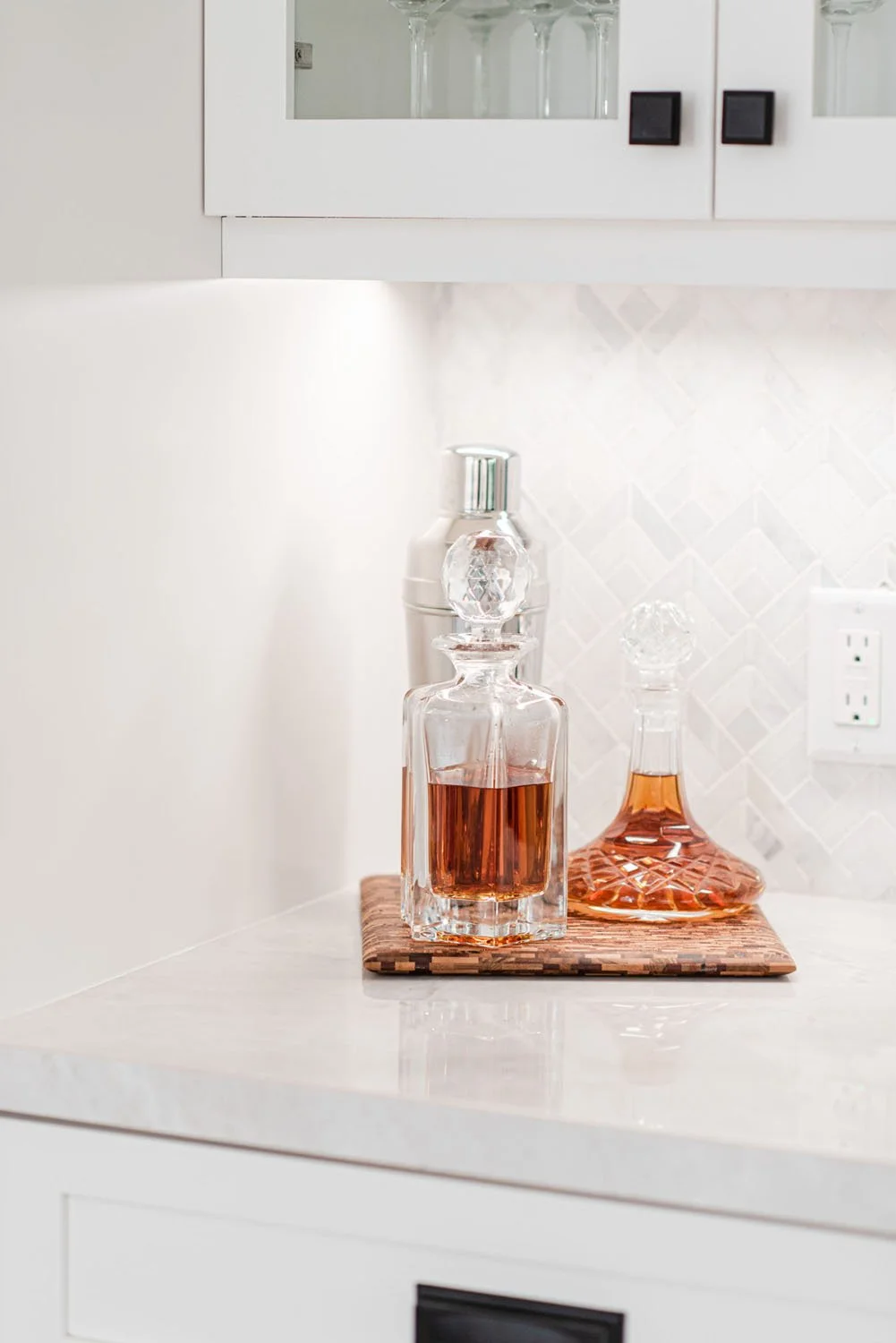 Quartz counter with glass decanters and white upper cabinets