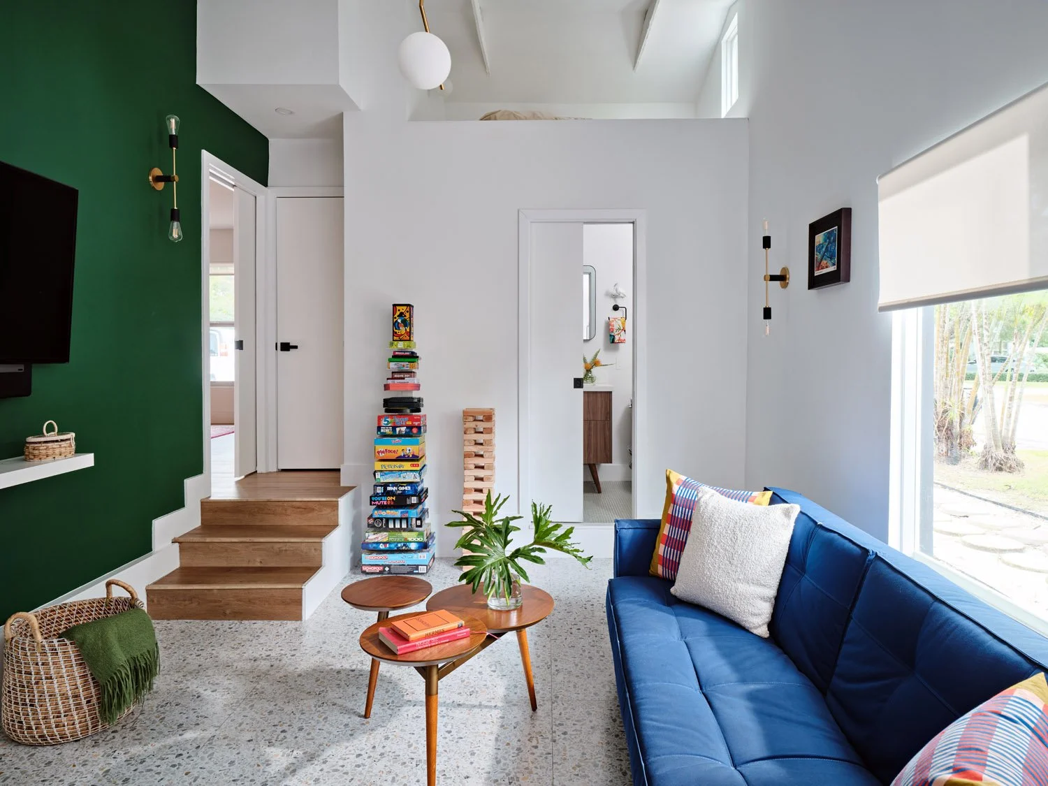 Family room with navy sofa, green accent wall and wood stairs