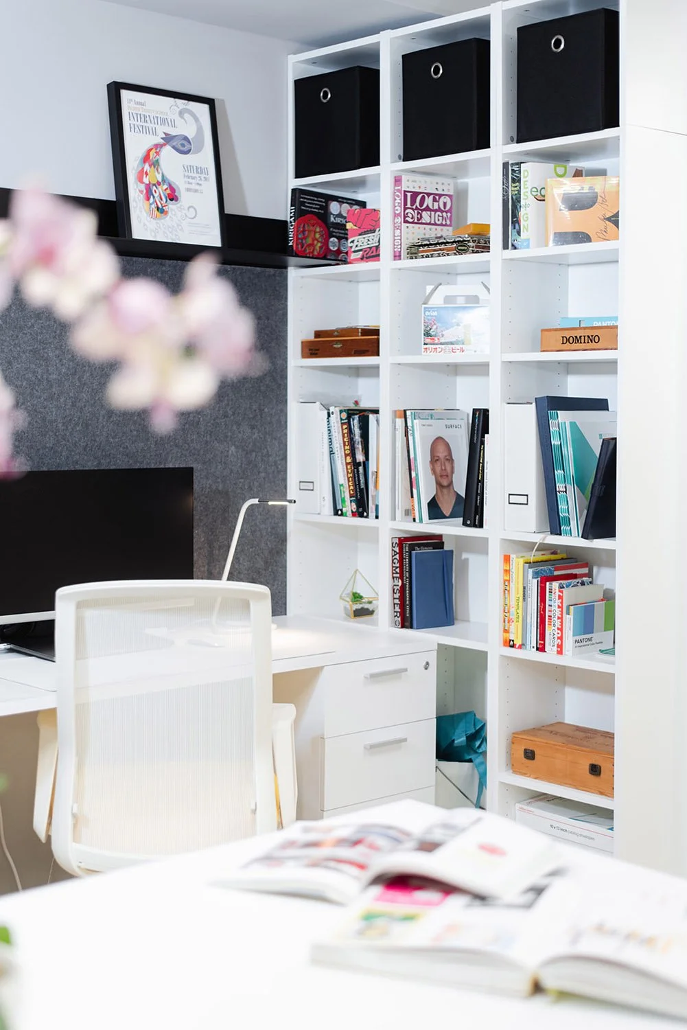 Bookshelf with storage bins beside a desk and cherry blossom branches