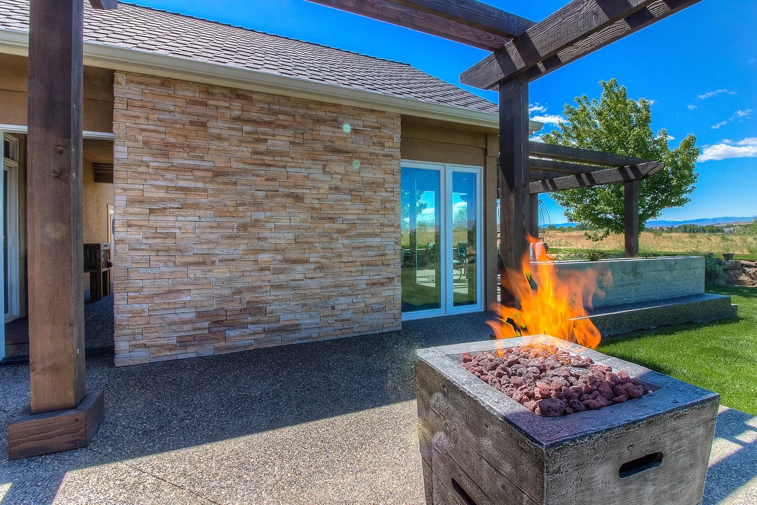 Square fire pit table under a wood pergola