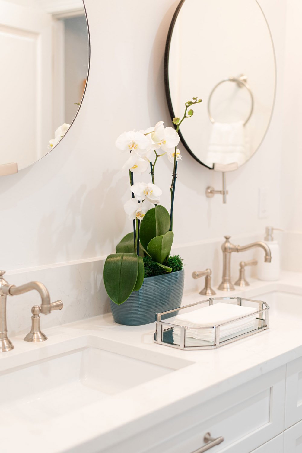 White vanity with round mirror and white orchid