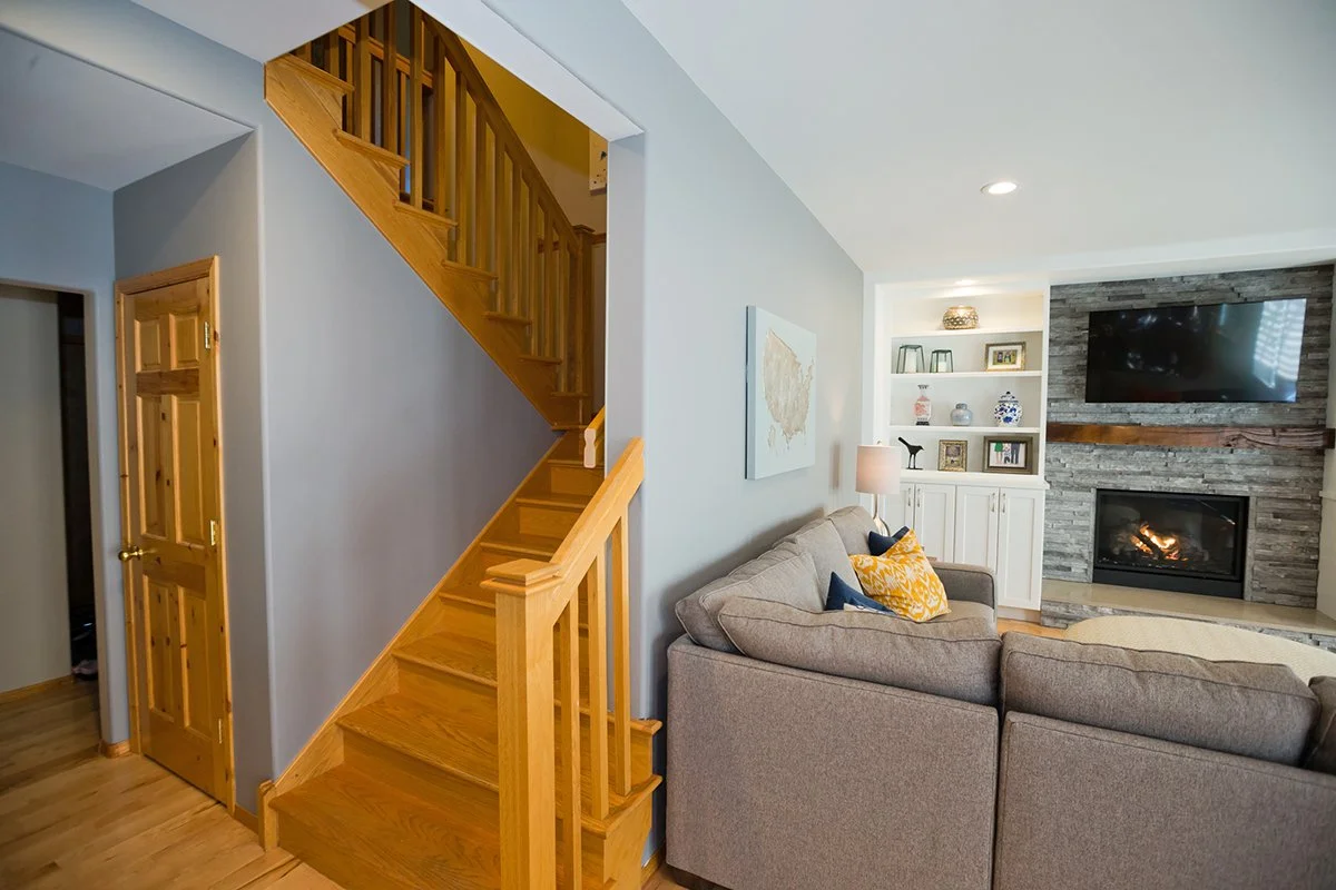 Family room with wood staircase, gray sectional and fireplace