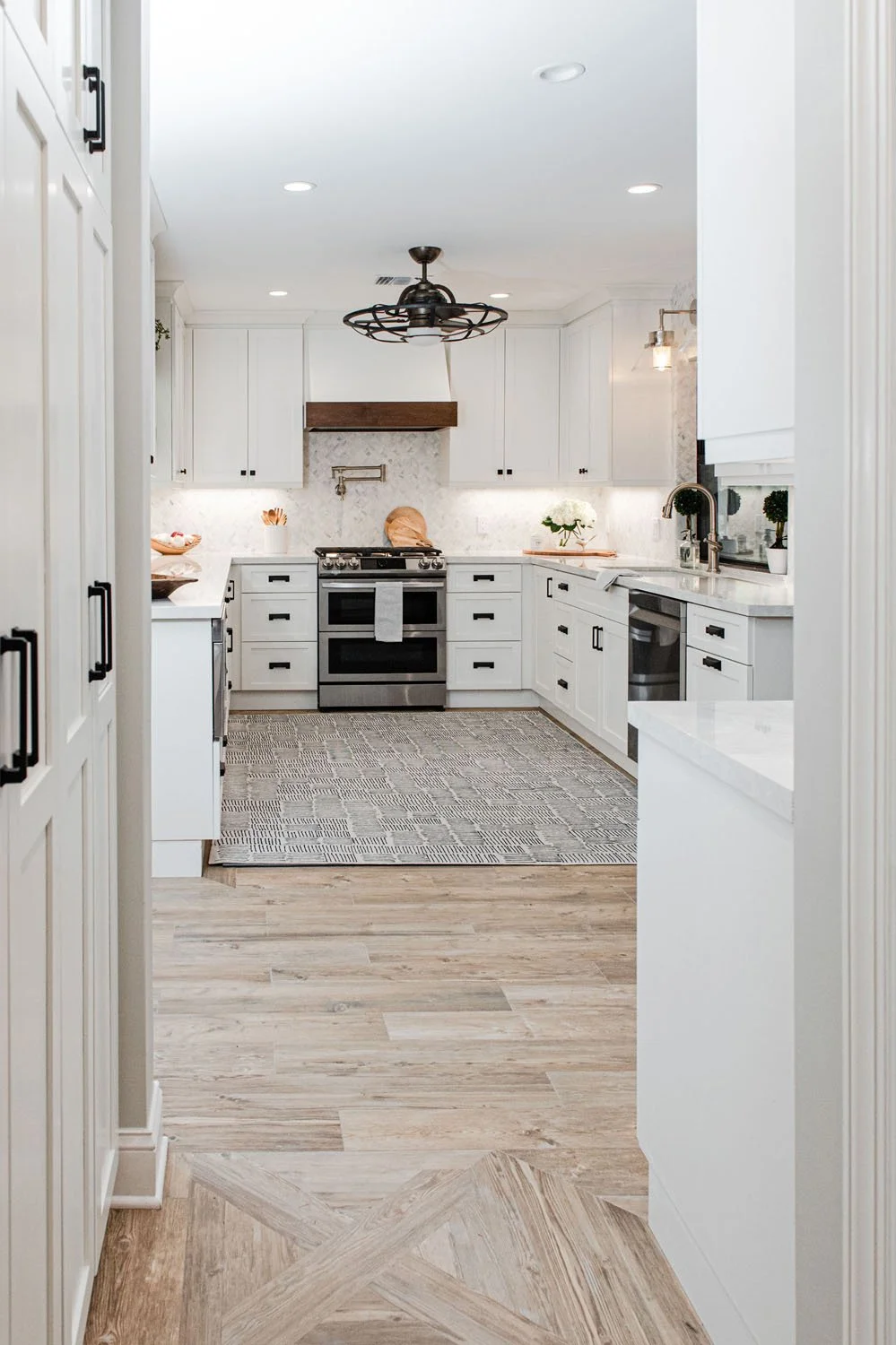 View down a hallway into a white U-shaped kitchen