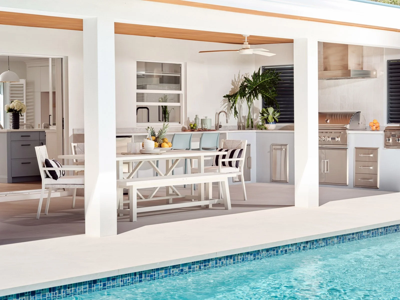 Pool deck with covered patio, outdoor kitchen and dining table