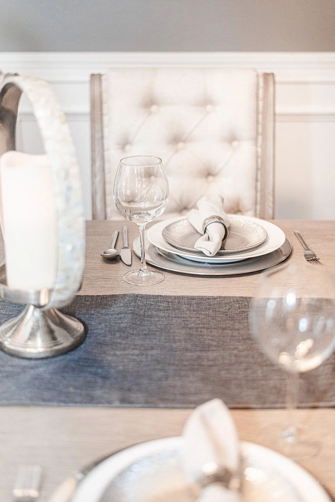 Place setting with silver charger and tufted dining chair
