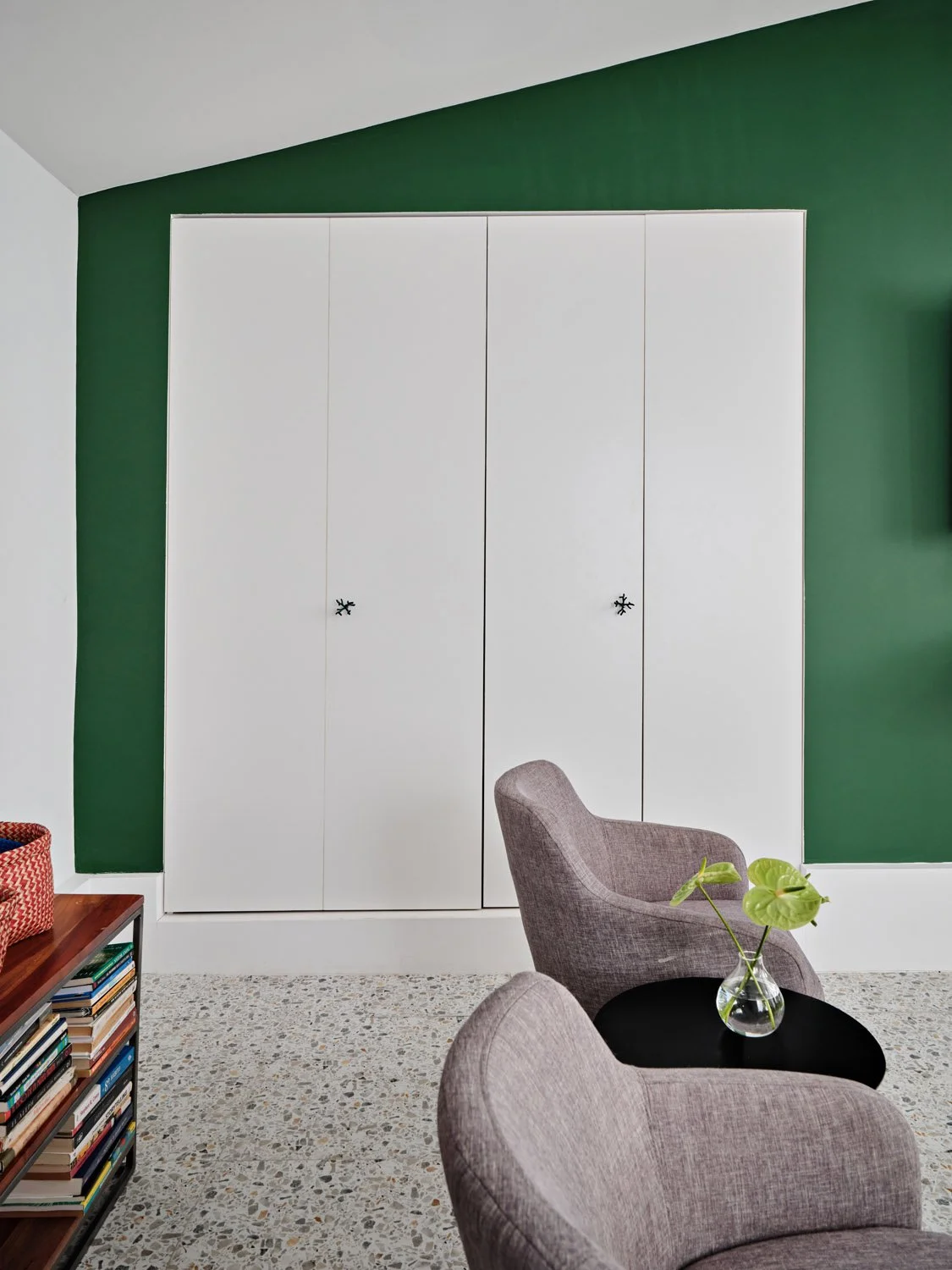 White closet doors on a green accent wall with gray chair