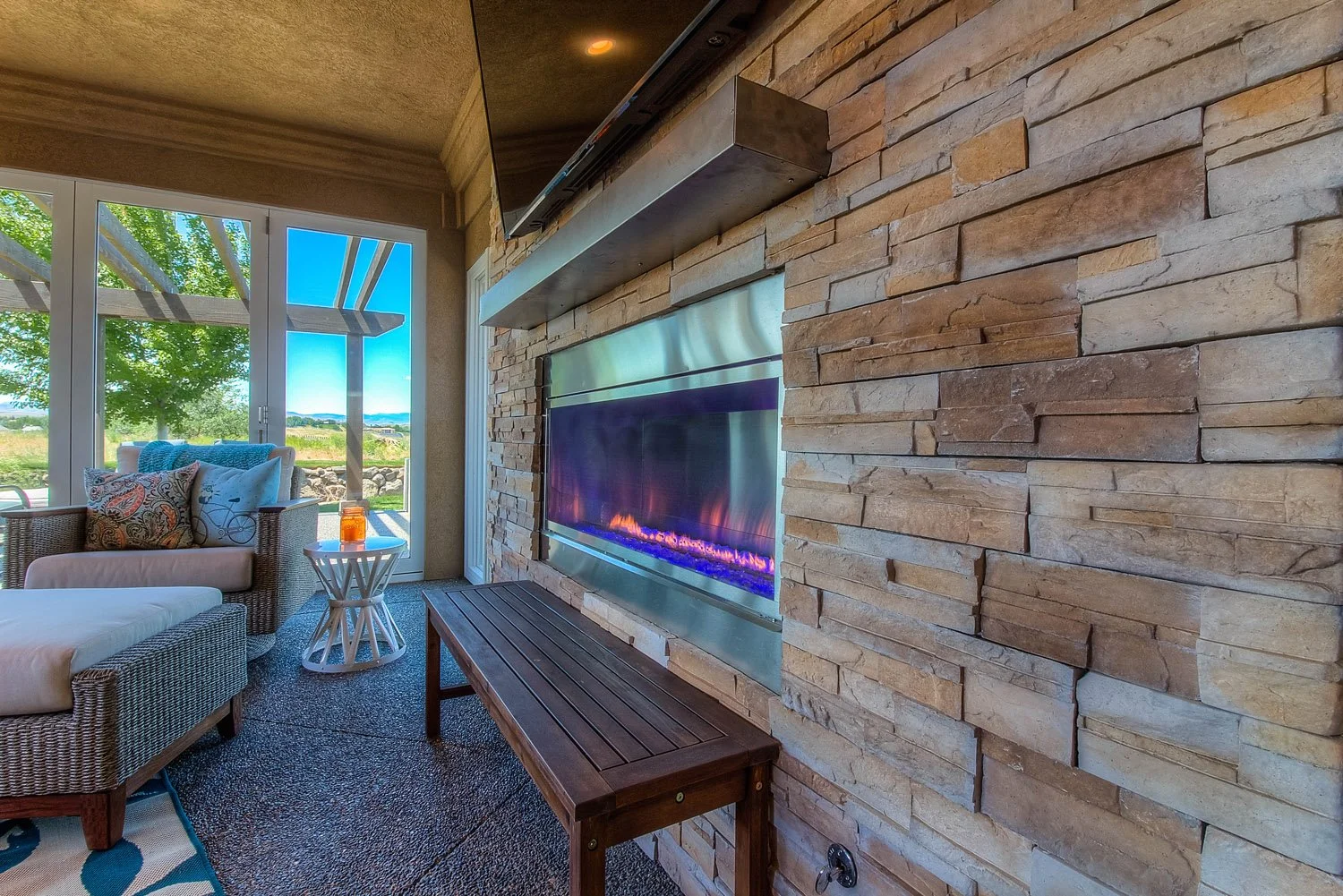 Linear fireplace set in a stacked stone wall in a sunroom