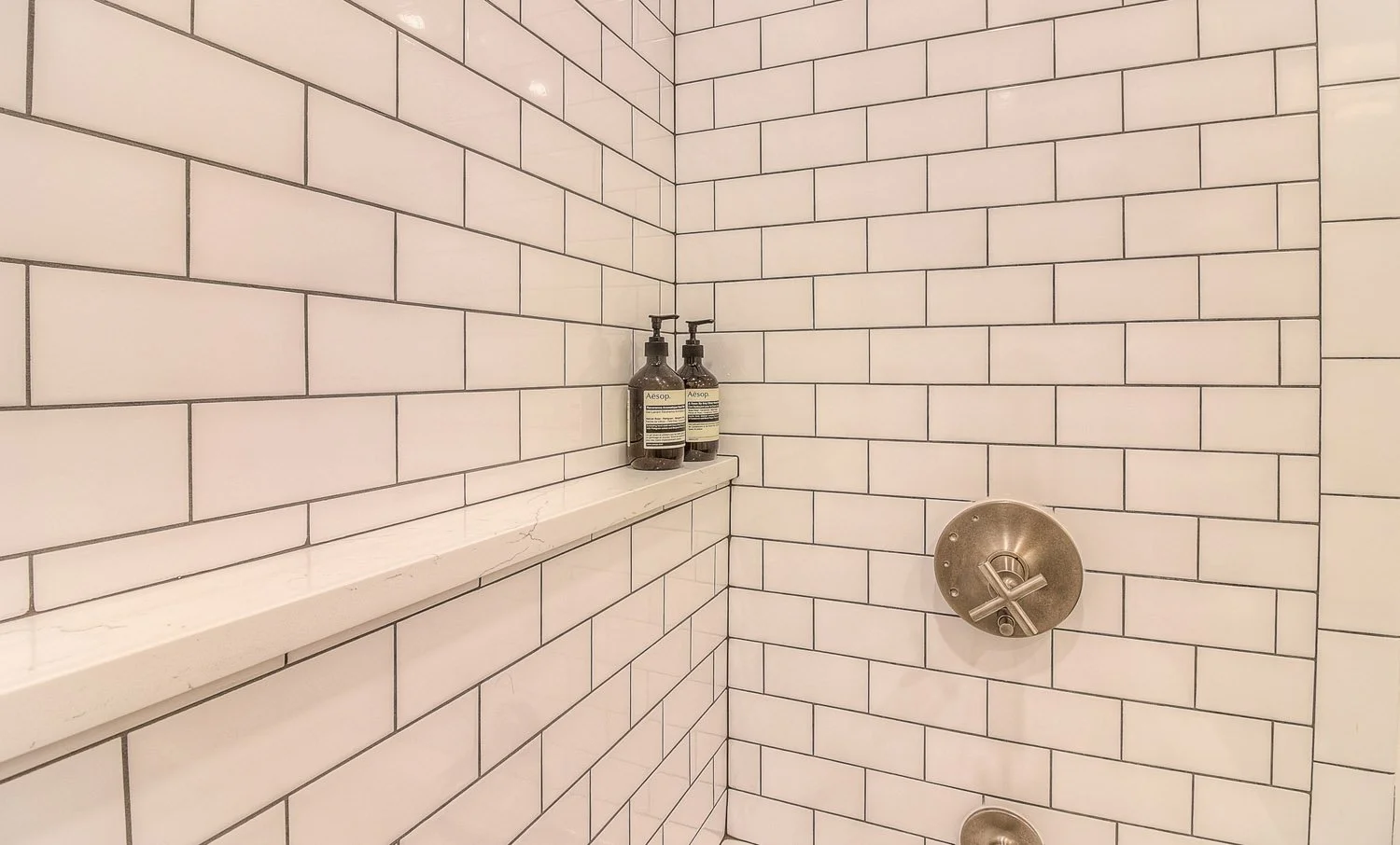 Subway tile shower with niche shelf and brushed fixtures