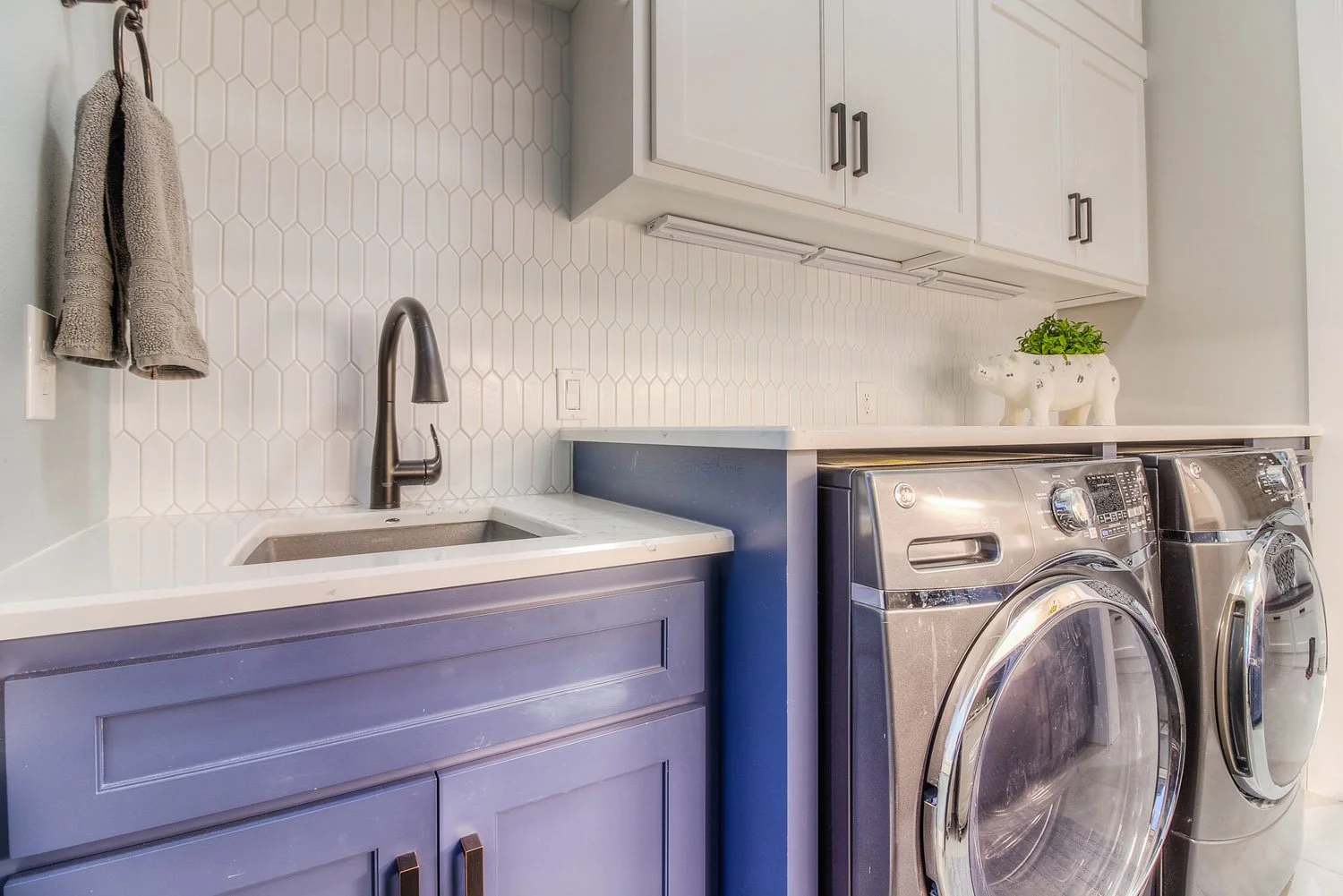 Laundry room with navy cabinets, front-load washer and dryer