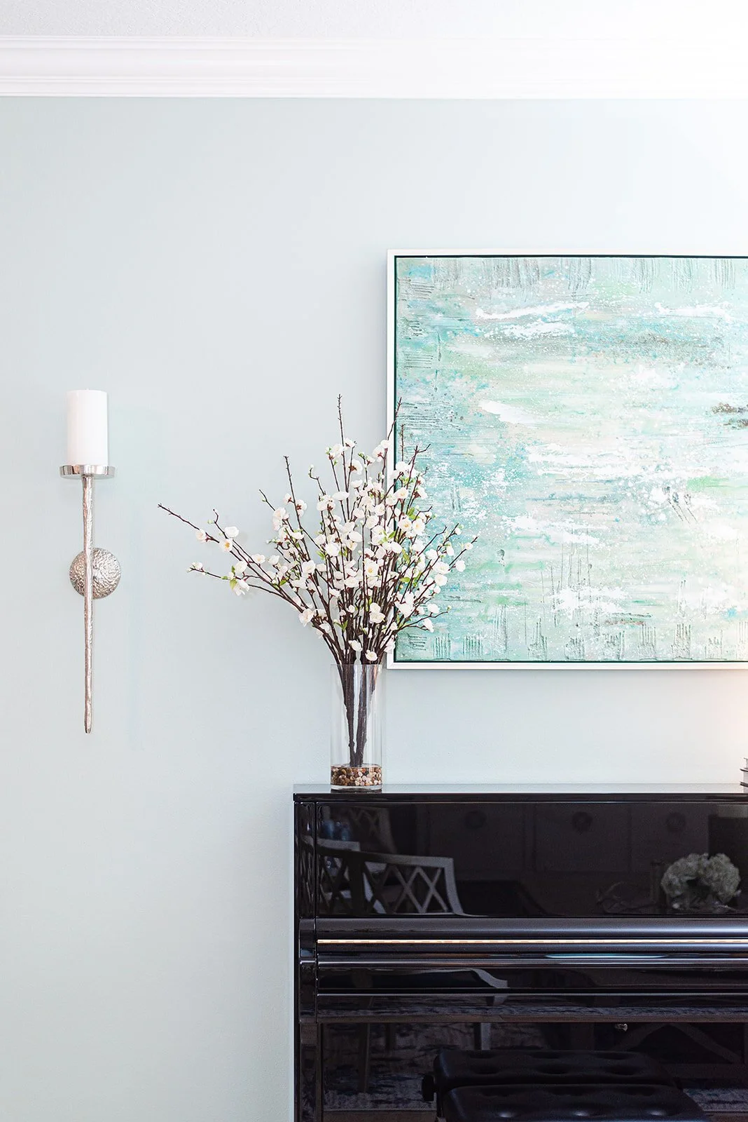 Black piano with abstract blue painting and branch arrangement