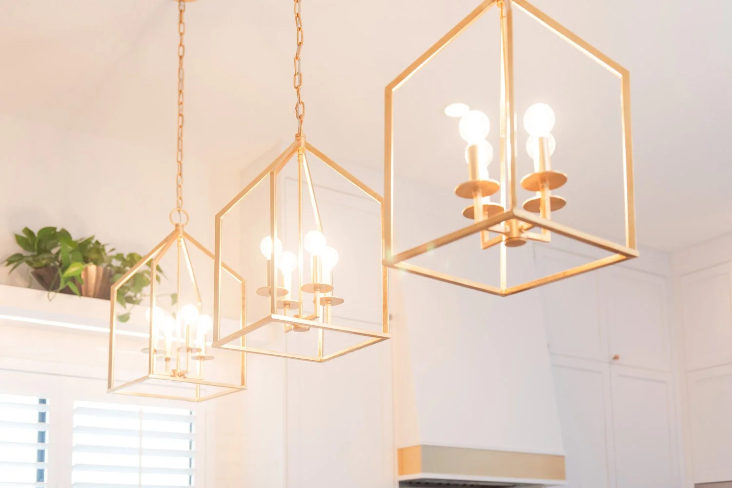 Brass geometric lantern pendants over a kitchen island
