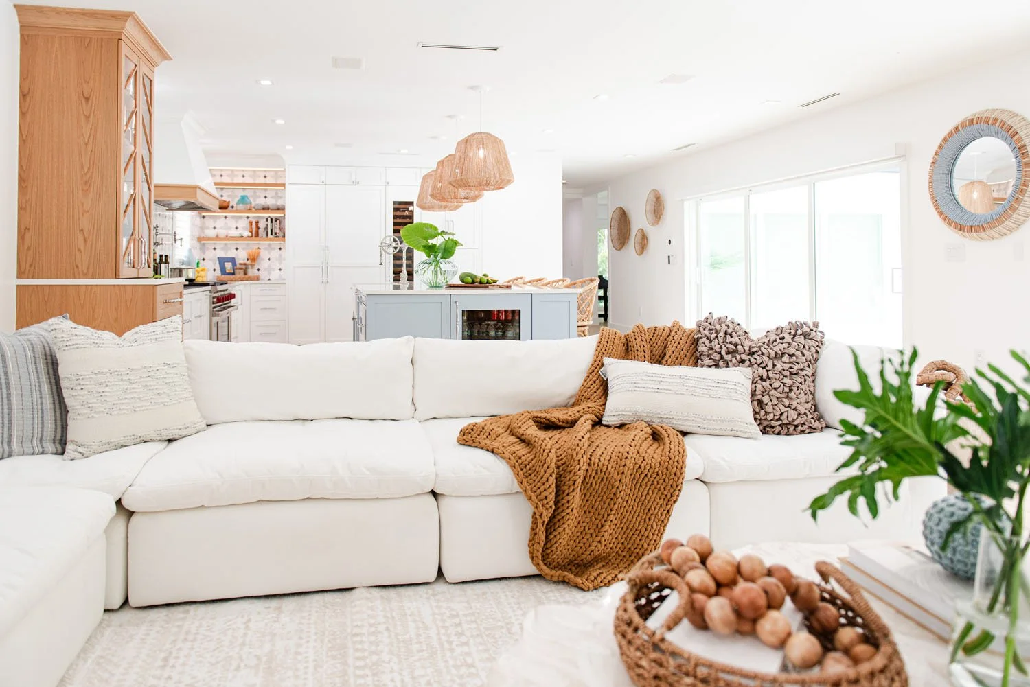 Living room with white sectional, cognac throw and rattan chair