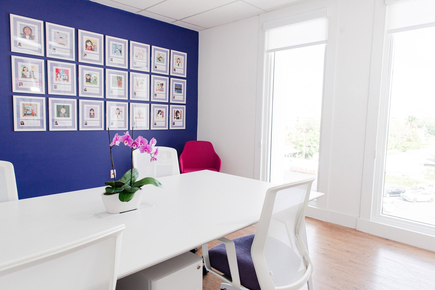 Navy accent wall with framed prints and white work table